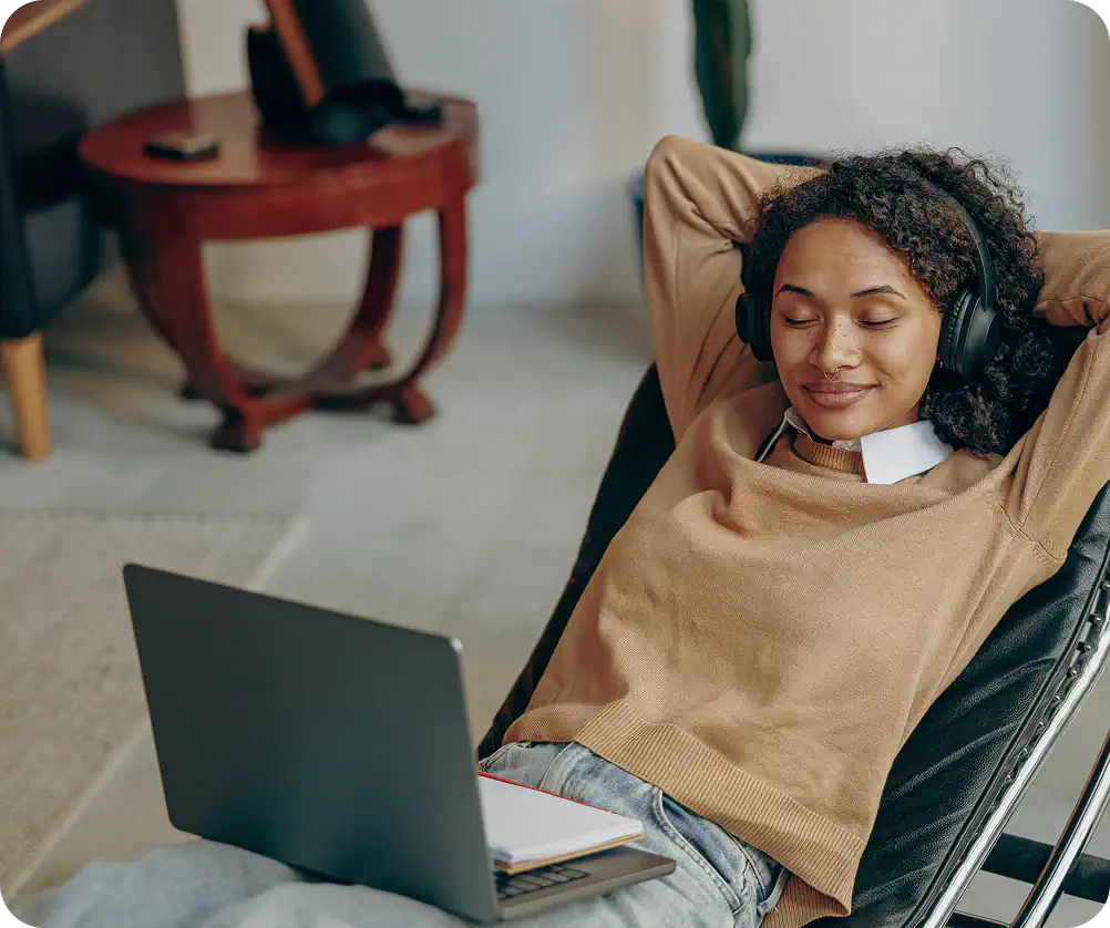 Smiling woman with headphones relaxing with laptop